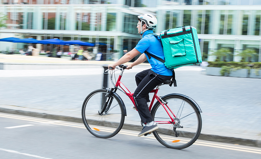 Courier On Bicycle Delivering Food In City