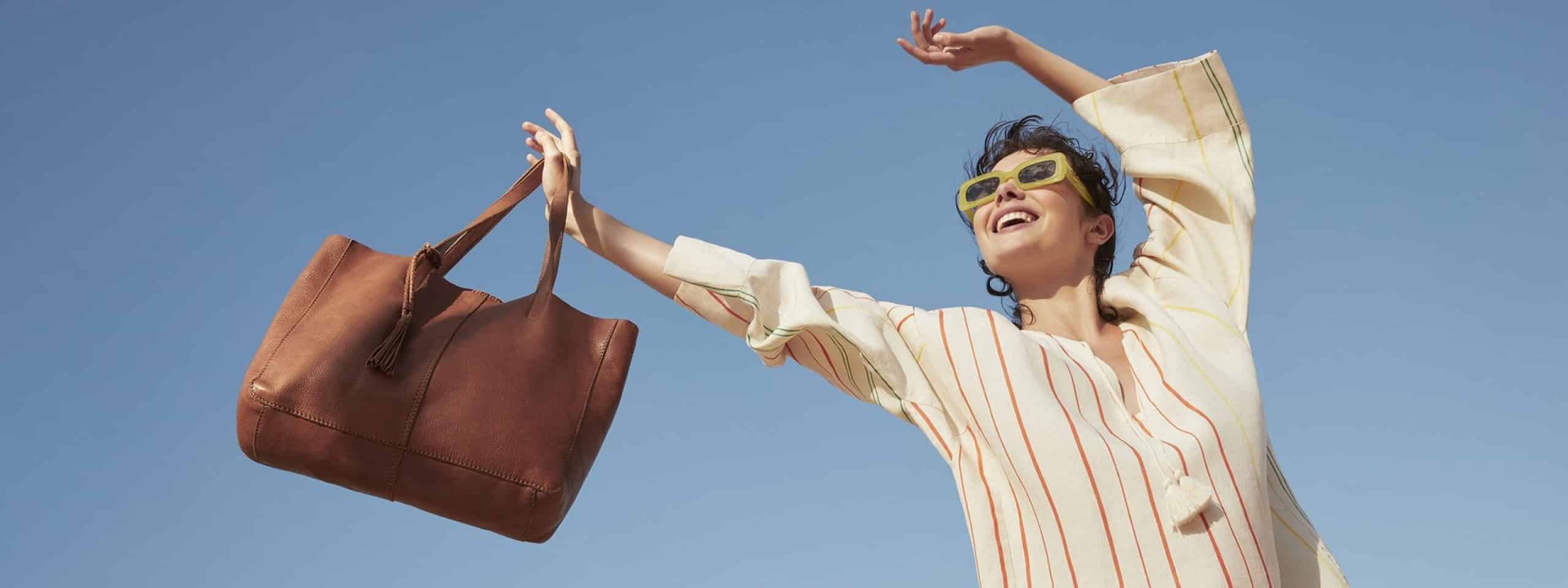 A woman holding a handbag in the sunlight