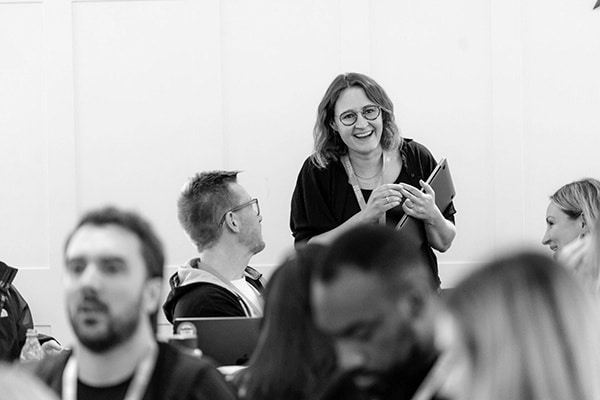 A member of the Equal Experts network smiles as they speak with other colleagues during a coworking day.