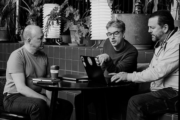 Three members of the Equal Experts Data team discuss a project while looking at a laptop screen.