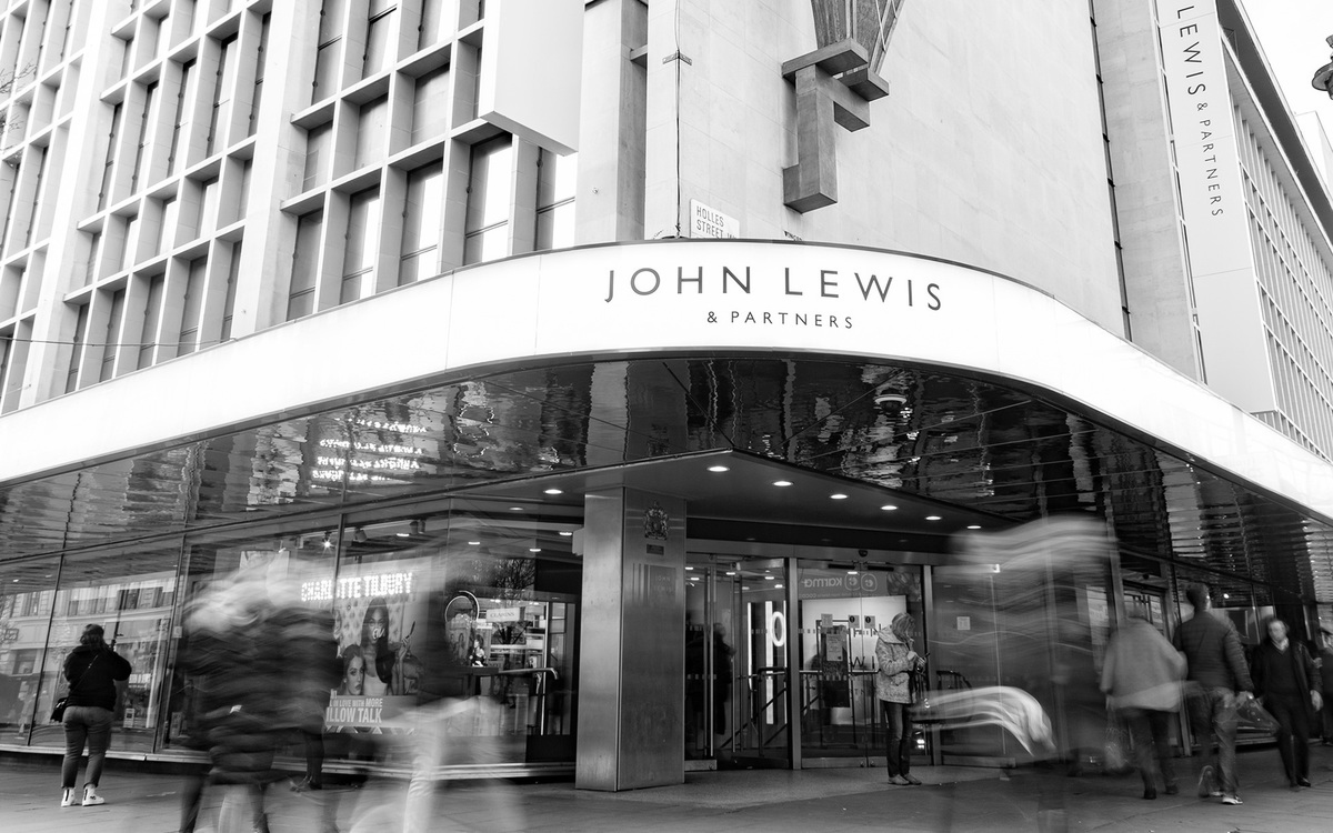 Front of a John Lewis store showing people walking in front of and into the store.