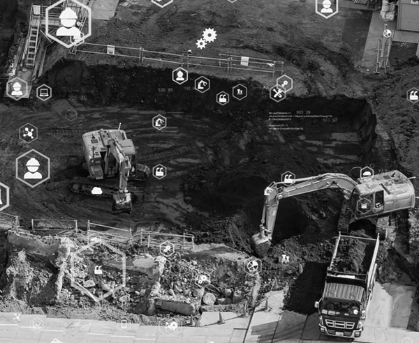 A birds eye view of a construction site, with technology icons hovering around the site and equipment.