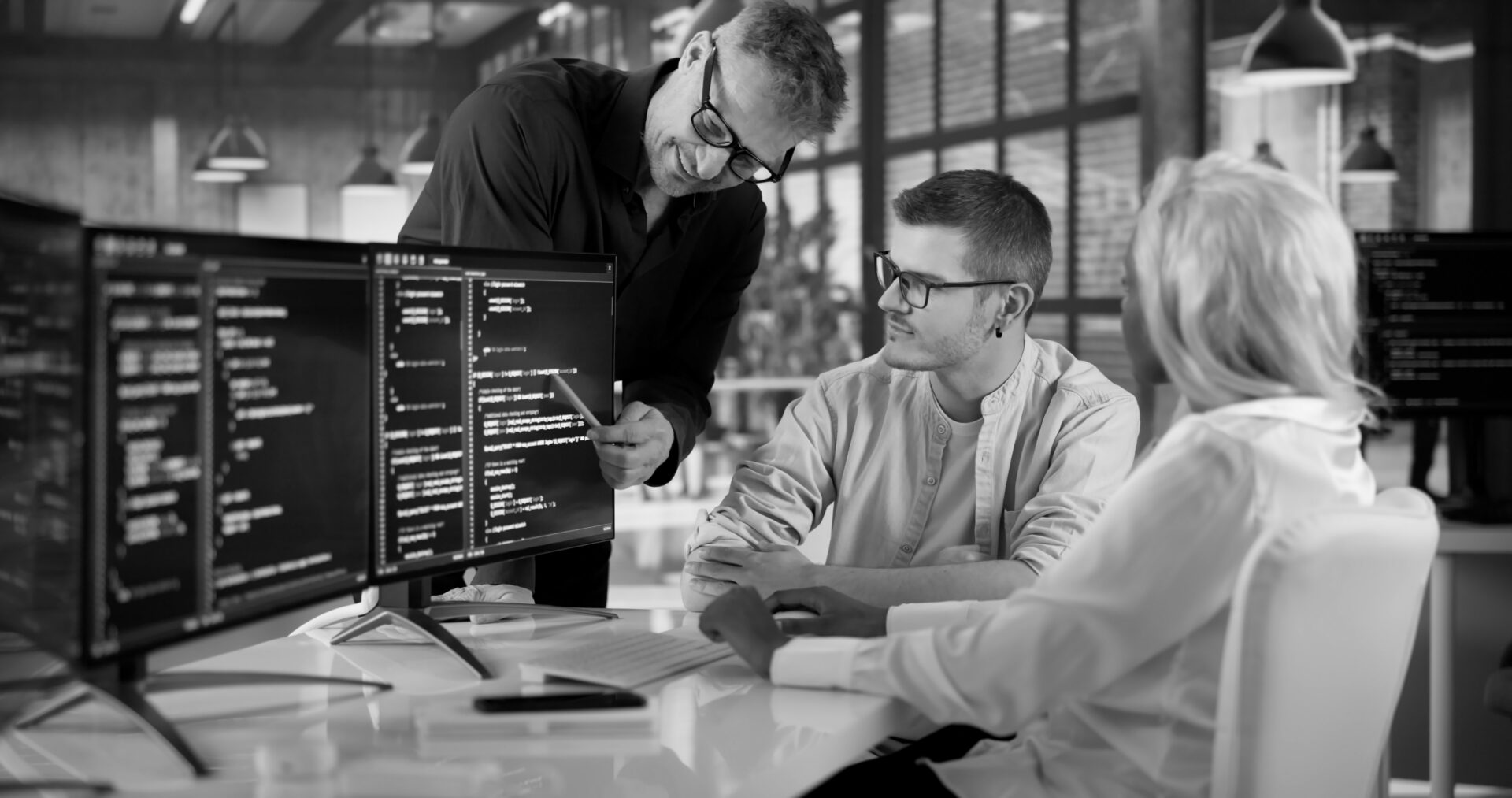 Software engineering team collaborating around code review and AI-supported delivery workflows in a modern office